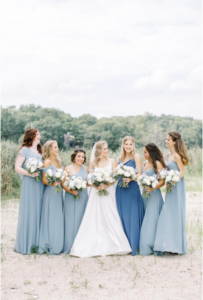 Summer garden-style bride and bridesmaids' bouquets with white garden roses and light blue delphiniums, with light dusty blue bridesmaids' dresses.