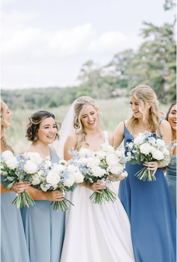 Summer garden-style Bride's bouquet with white garden roses and light blue delphiniums, with light dusty blue bridesmaids' dresses.
